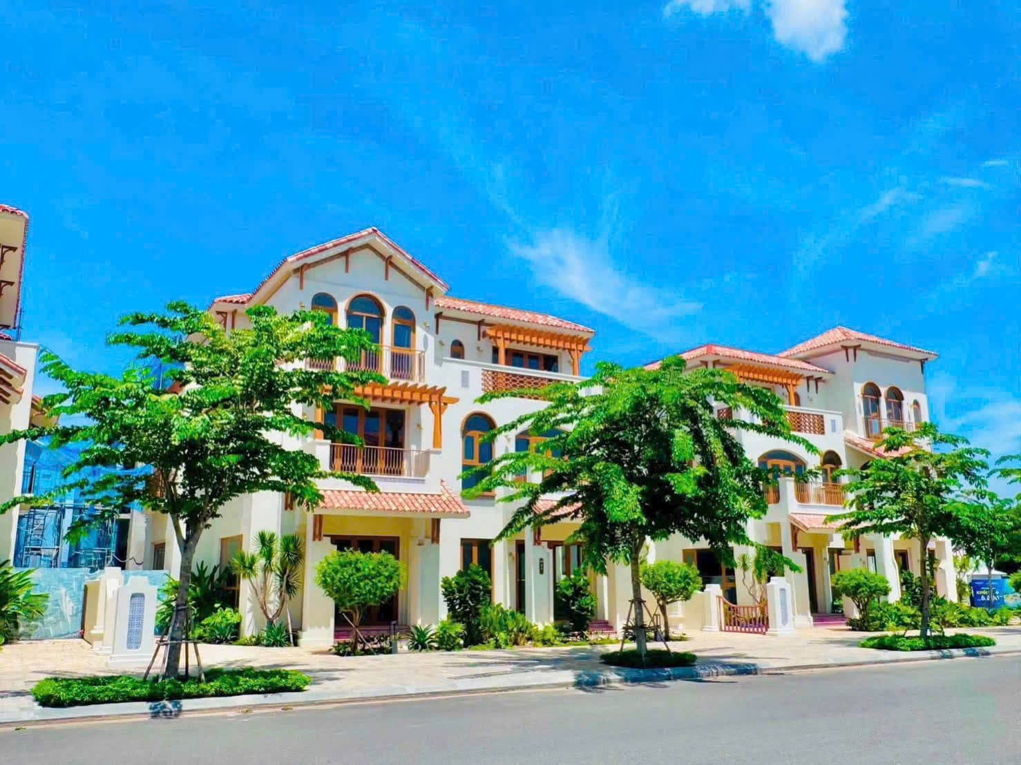 Hai căn biệt thự trắng mái ngói với hàng cây xanh mới trồng phía trước ven đường nội khu