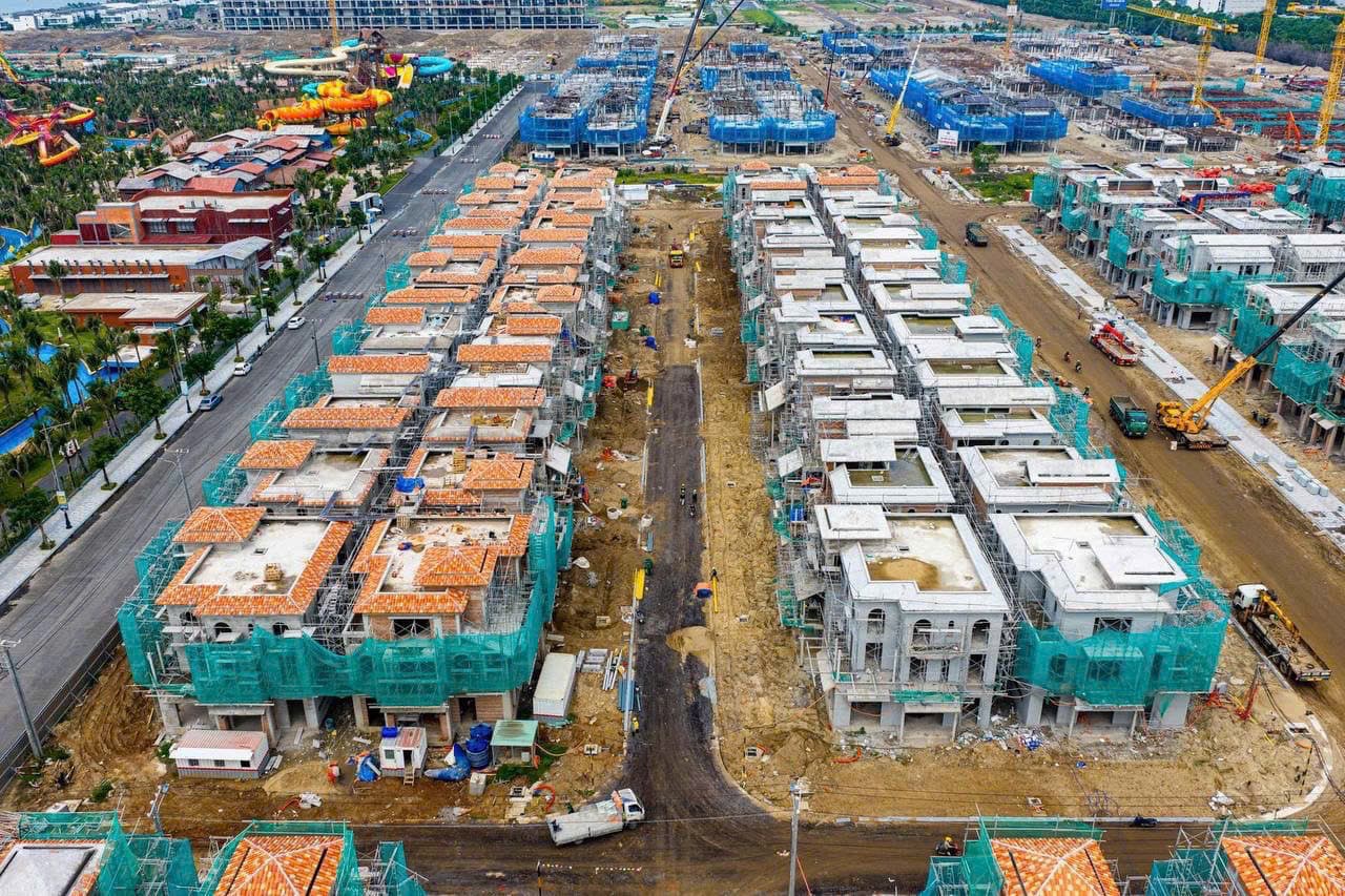 Dãy biệt thự đang xây phủ lưới xanh, cần cẩu và xe tải trên công trường