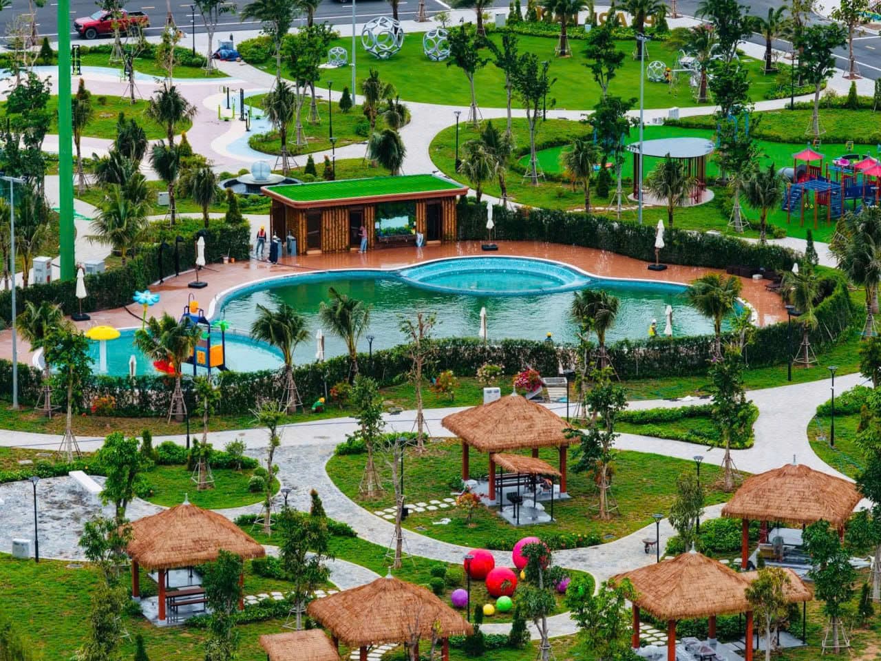 Ảnh chụp công viên nội khu đã hoàn thiện với bể bơi, chòi mái lá và bãi cỏ